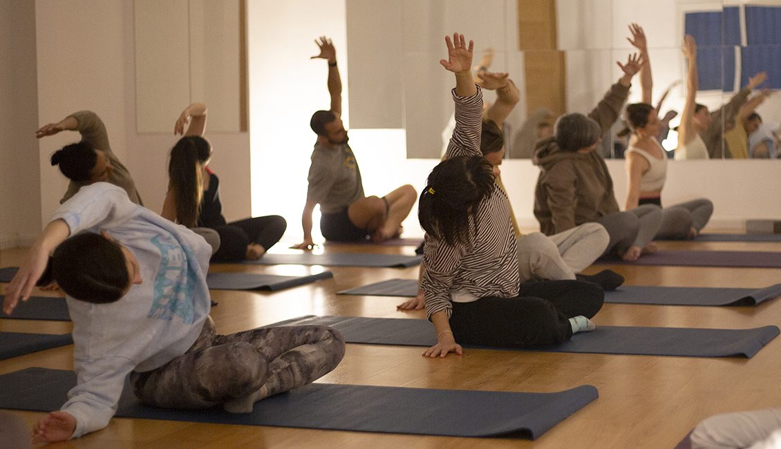 Vinyasa-Yoga-clase-estudiantes-extensión-lateral-sentada